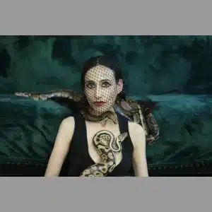 A woman sitting on a couch, fearlessly holding a snake in her hands.