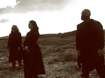 A black and white photo of a group of people standing in a field.