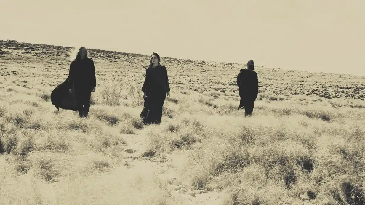 A black and white photo captures a group of people in the desert, radiating an air of Tryst Arcane.