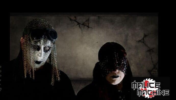 Two individuals wearing dark, gothic attire and masks with a sinister aesthetic.