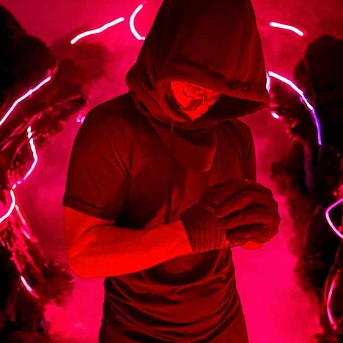 A person in a hooded outfit stands against a backdrop of vivid red lighting, with bright streaks creating an Elementor-like intense visual effect.